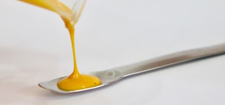 colher sendo enchida por líquido amarelo
