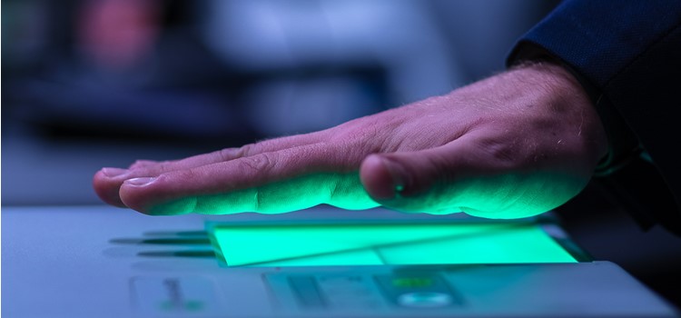 Foto de mão branca sobre máquina de leitura palmar que emite luz verde. fundo da foto desfocado. fim da descrição