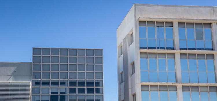 Fachada parcial de dois prédios do Parque Científico da Unicamp. Um tem paredes brancas e vidros espelhado e o outro é cinza e espelhado. Fim da descrição.