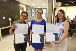 Foto colorida mostra três pessoas, sendo duas mulheres e um homem. Sócio da For Nano posa para foto, com certificado de graduação, ao lado de representantes da Inova.