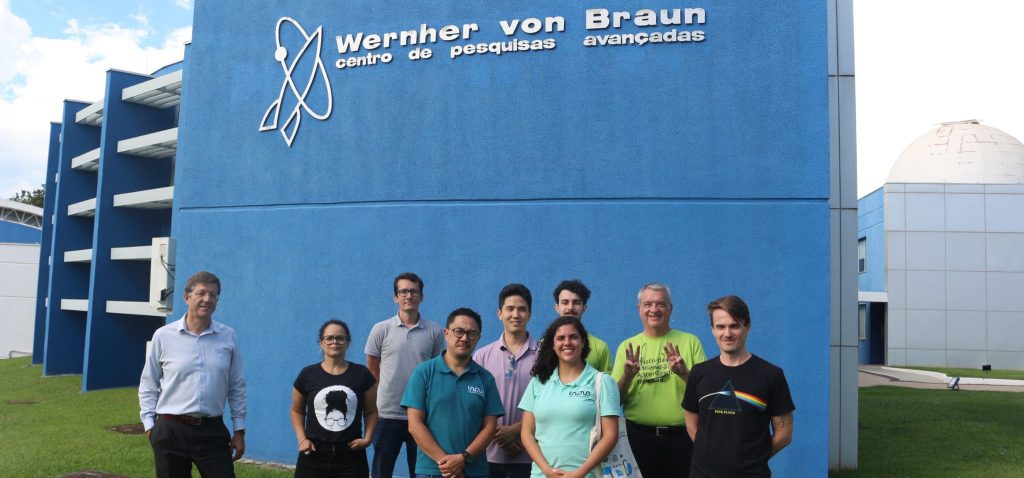 Foto feita em área externa. Nela, há representantes de startups incubadas na Incamp, colaboradores da Inova e do presidente do Instituto Von Braun. Todos encontram-se em pé, posando em frente a uma parede azul com o logo do espaço. Fim da descrição.