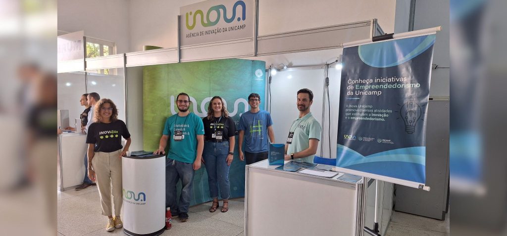 Estande e equipe da Inova Unicamp no evento Tecnologia em Foco. Fim da descrição.